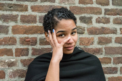 Portrait of a woman against brick wall