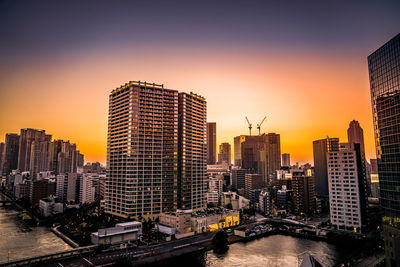 Modern buildings in city against sky during sunset