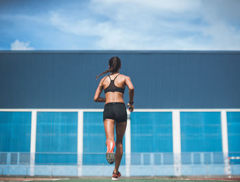 Rear view of woman running on playing field