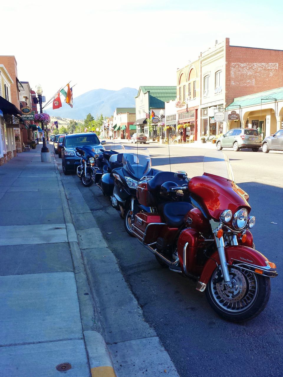 transportation, mode of transport, land vehicle, building exterior, street, stationary, car, built structure, architecture, parked, bicycle, parking, city, incidental people, in a row, sky, road, travel, clear sky, outdoors