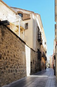 Footpath amidst buildings in town against sky