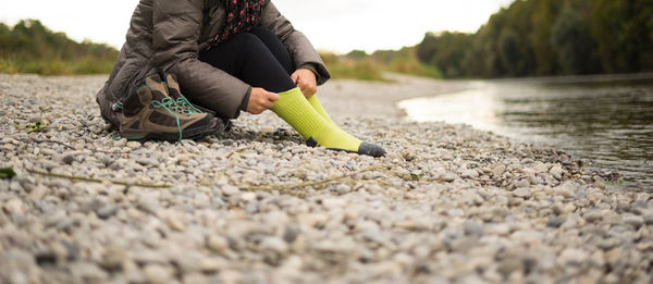 Low section of woman wearing sock at riverbank