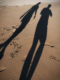 Shadow of people on sand at beach