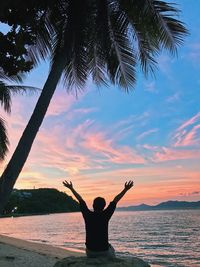 Man sitting at beach during sunset