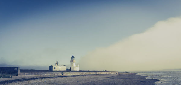 Lighthouse amidst buildings against sky