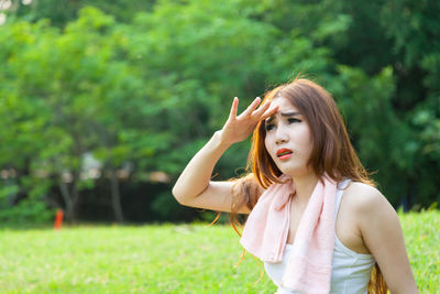 Woman shielding eyes while sitting on field