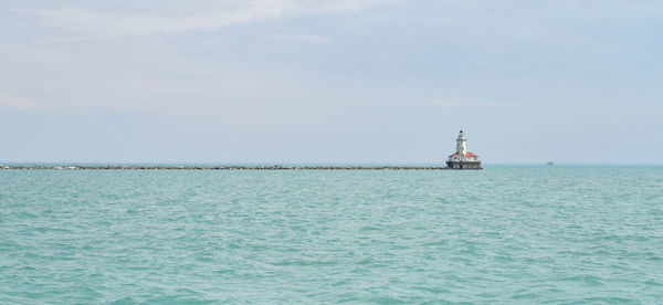 Lighthouse by sea against sky