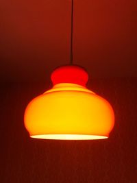 Close-up of illuminated light bulb against orange wall