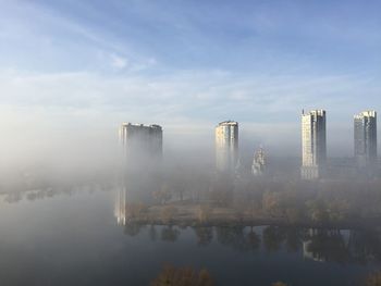 Reflection of buildings in lake against sky