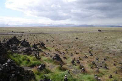 Scenic view of field against cloudy sky