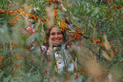 Portrait of smiling young woman against plants