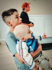 Boy carrying brother on hardwood floor