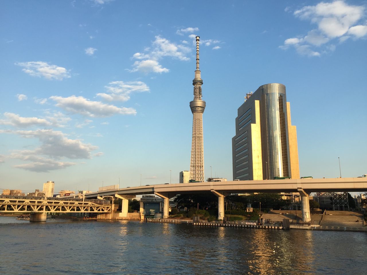 water, built structure, architecture, reflection, sky, building exterior, waterfront, cloud - sky, day, low angle view, outdoors, city, no people, high angle view, metal, cloud, standing water, river, travel destinations, blue