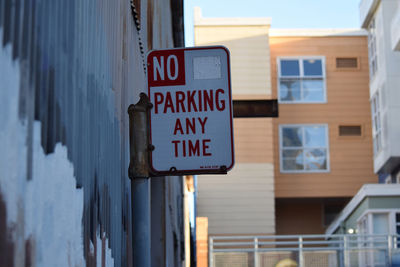 Low angle view of text on sign board against buildings