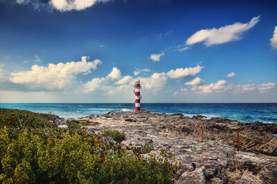 Lighthouse by sea against sky