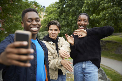 Happy friends looking at smart phone while practicing dance at park