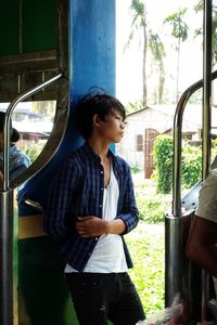 Young man looking away while standing in train