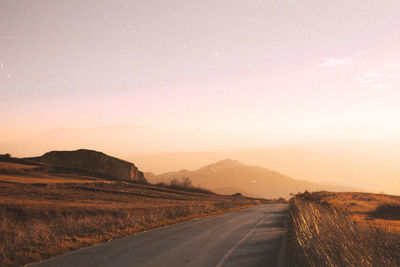 Road on landscape against sky during sunset