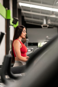 A pretty caucasian woman using a treadmill at the gym