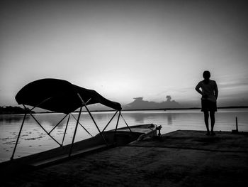 Silhouette people looking at sea shore against sky
