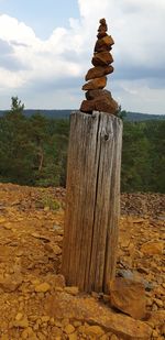 Stack of wooden post on field against sky