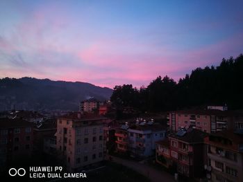 Buildings in town against sky at sunset