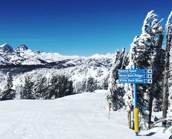 Information sign on snowcapped mountain against blue sky