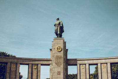 Low angle view of sculpture on building against blue sky