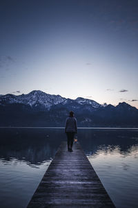 Rear view of man standing on lake against sky