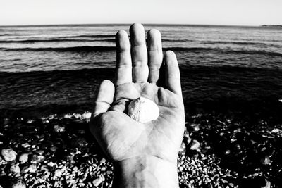 Close-up of human hand against sea