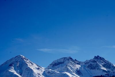 Scenic view of snowcapped mountains against blue sky