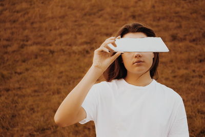 Woman covering eyes with mirror against plants