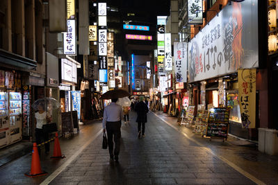 People walking on illuminated city at night