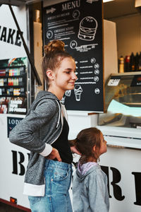 Teenage girl and her younger sister waiting for their order at front of a food truck
