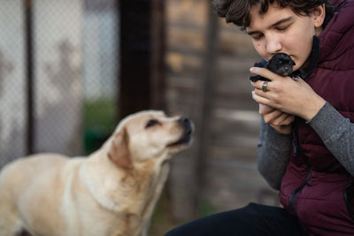 The guy gently presses the puppy to his face, the dog the mother worries about the puppy