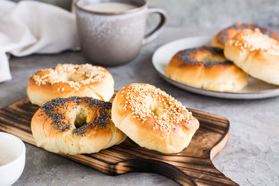 Bagels with poppy seeds and sesame seeds on a plate and a cup of coffee on the table. 