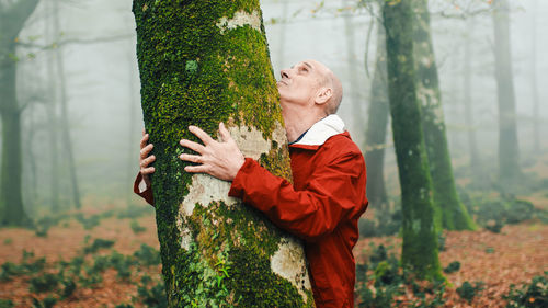 Elderly man hugging trees in the mountains to relax