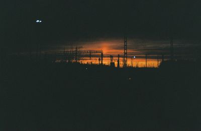 Silhouette of illuminated lights against sky at night