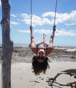 Portrait of smiling woman swinging at beach