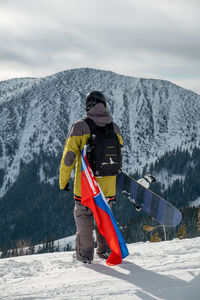 Rear view of man standing on snow covered mountain