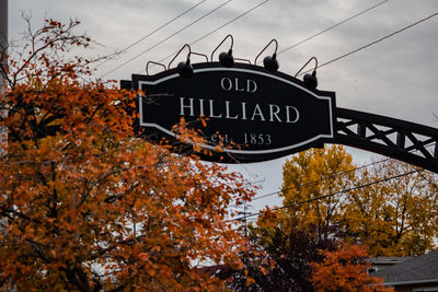 Low angle view of information sign against sky during autumn