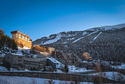 Small soldeu town surrounded by pine forest and snow capped mountain range, andorra