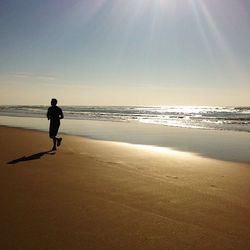 Silhouette man on beach against sky during sunset