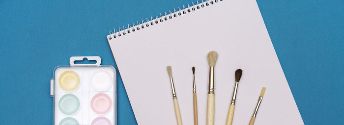 High angle view of paintbrushes on table against blue background