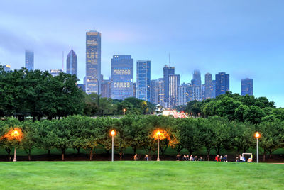 Illuminated trees and buildings against sky at dusk