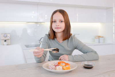 Portrait of young woman sitting on table at home