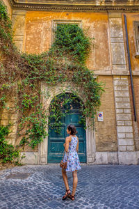 Full length rear view of woman standing against building