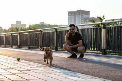 Handsome european man in sunglasses is walking with dog on a street.