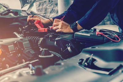 Cropped hands of mechanic repairing car in garage