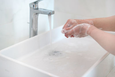 Cropped hand washing hands in bathroom